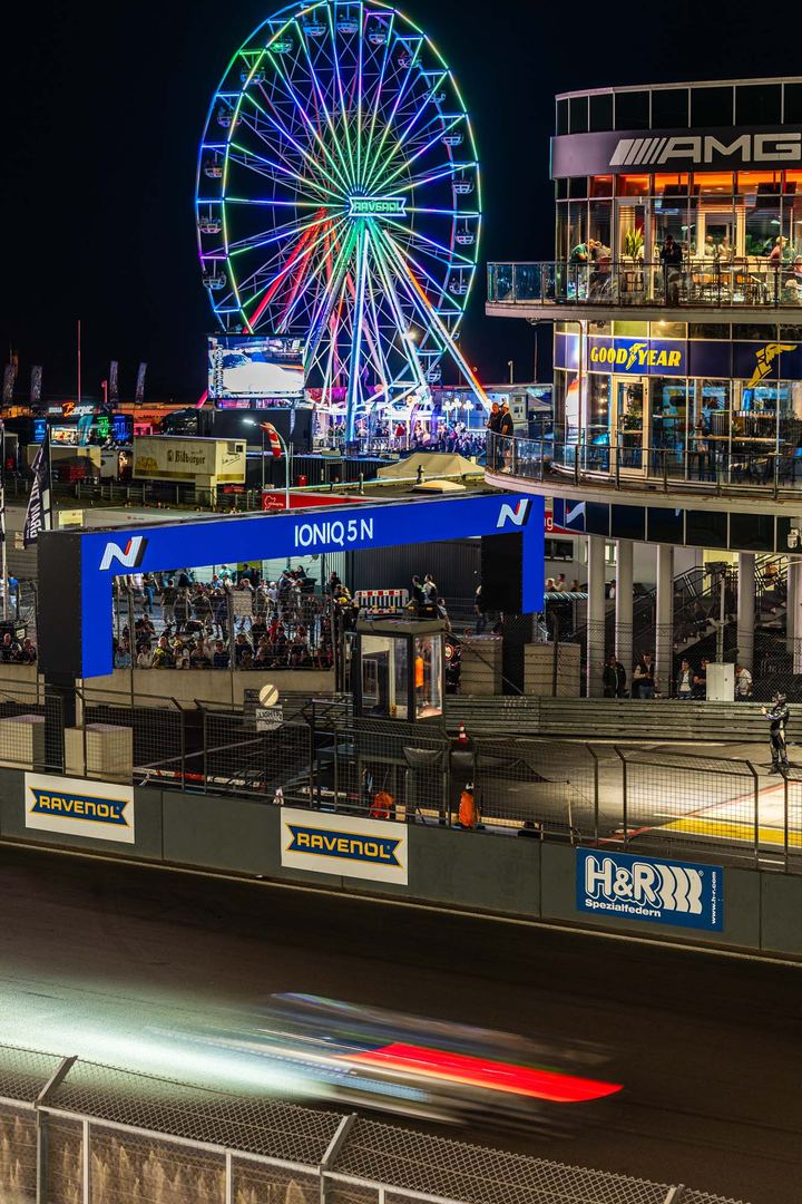 Rennstrecke bei Nacht mit beleuchtetem Riesenrad
